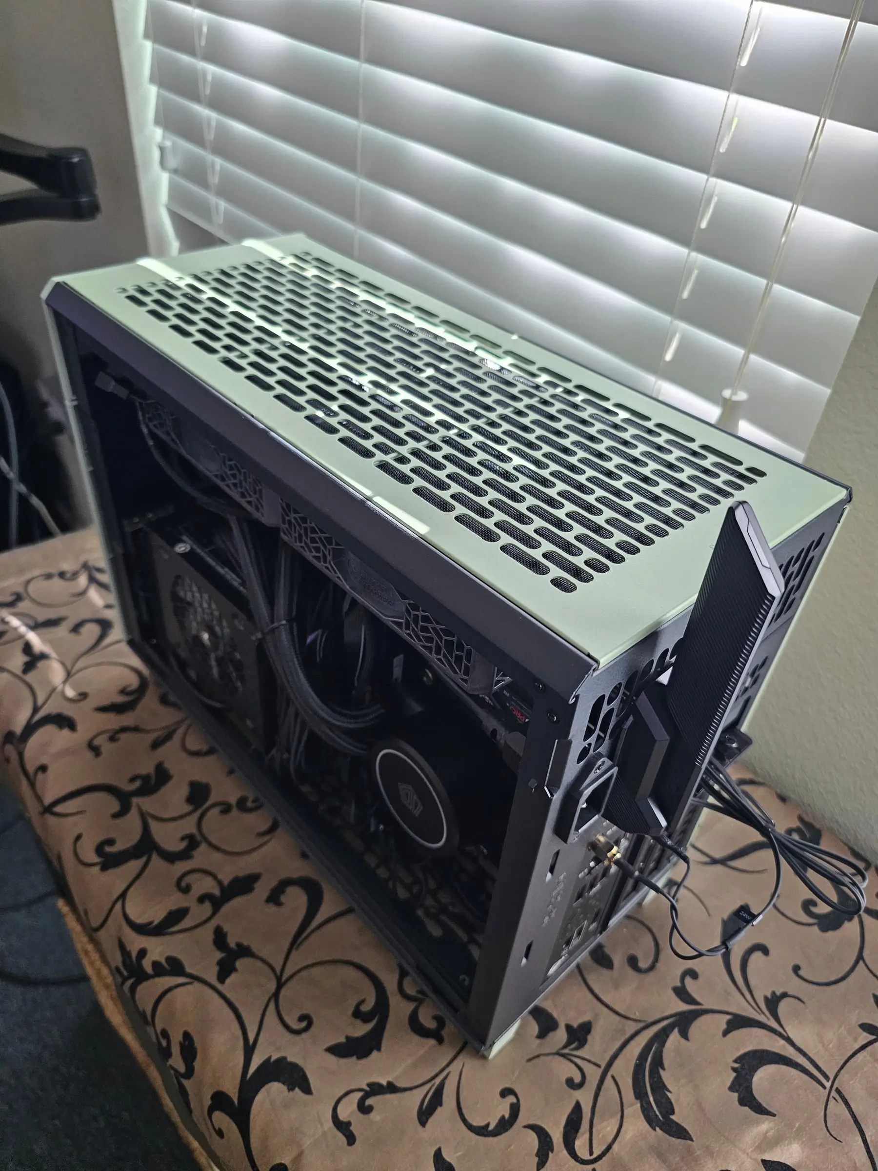 Rear three-quarter view with the panel off, showing the AIO radiator and power supply installed in the compact chassis