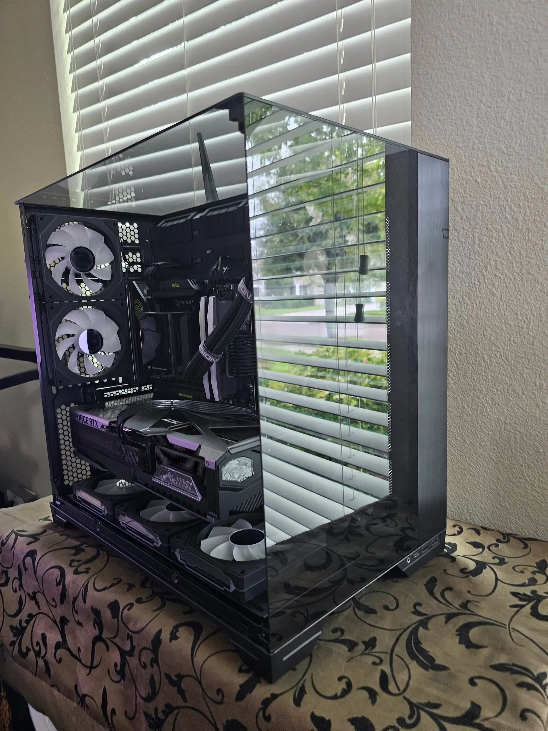 All-black O11 Vision in daylight — MSI RTX 5090 Vanguard, MAG X870 Tomahawk, and Hyper Vision AIO behind three glass panels