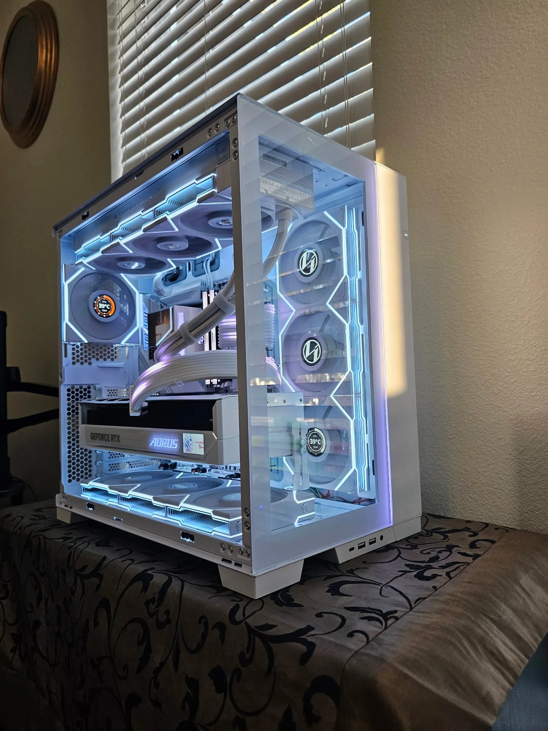 Frost-white EVO RGB three-quarter — Aorus Master Ice card, temp dials on the fan LCDs, edge strips glowing ice blue