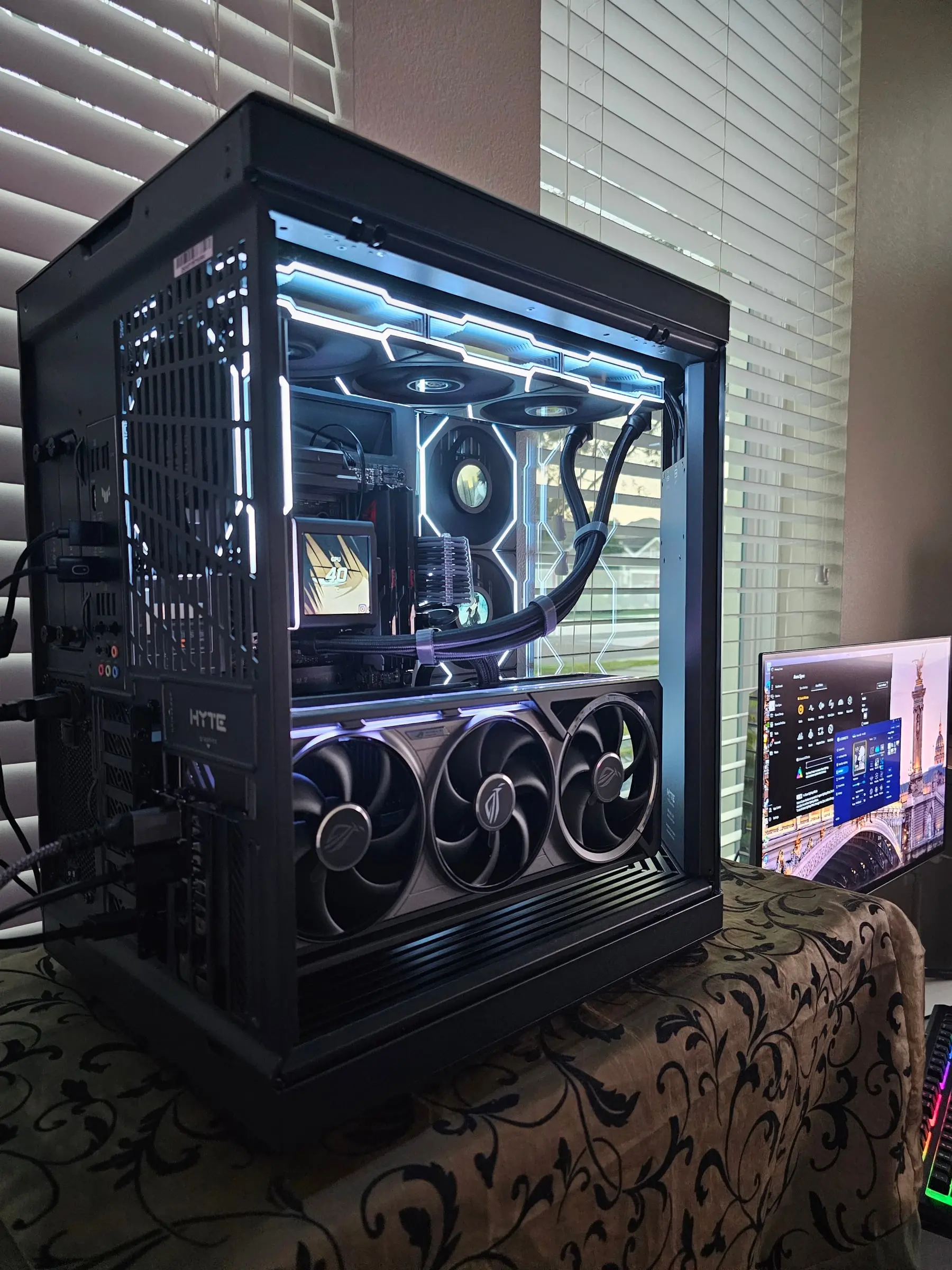 Rear three-quarter with the TUF rear I/O, Astral RTX 5080 triple fans, and the Galahad LCD reading GPU temps