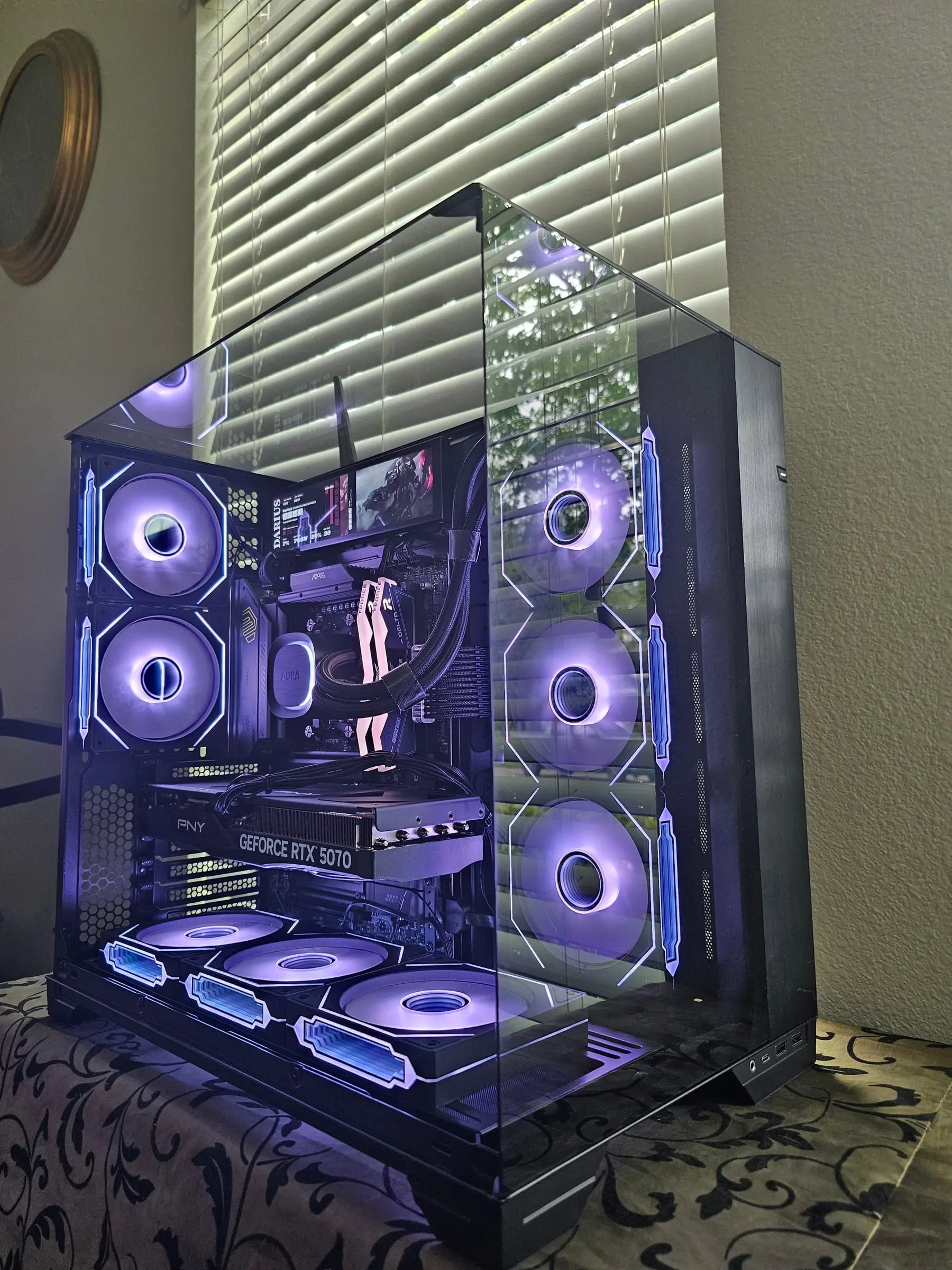Violet theme through the pillarless glass corner — AURA pump, white T-Force Delta RAM, and the PNY RTX 5070