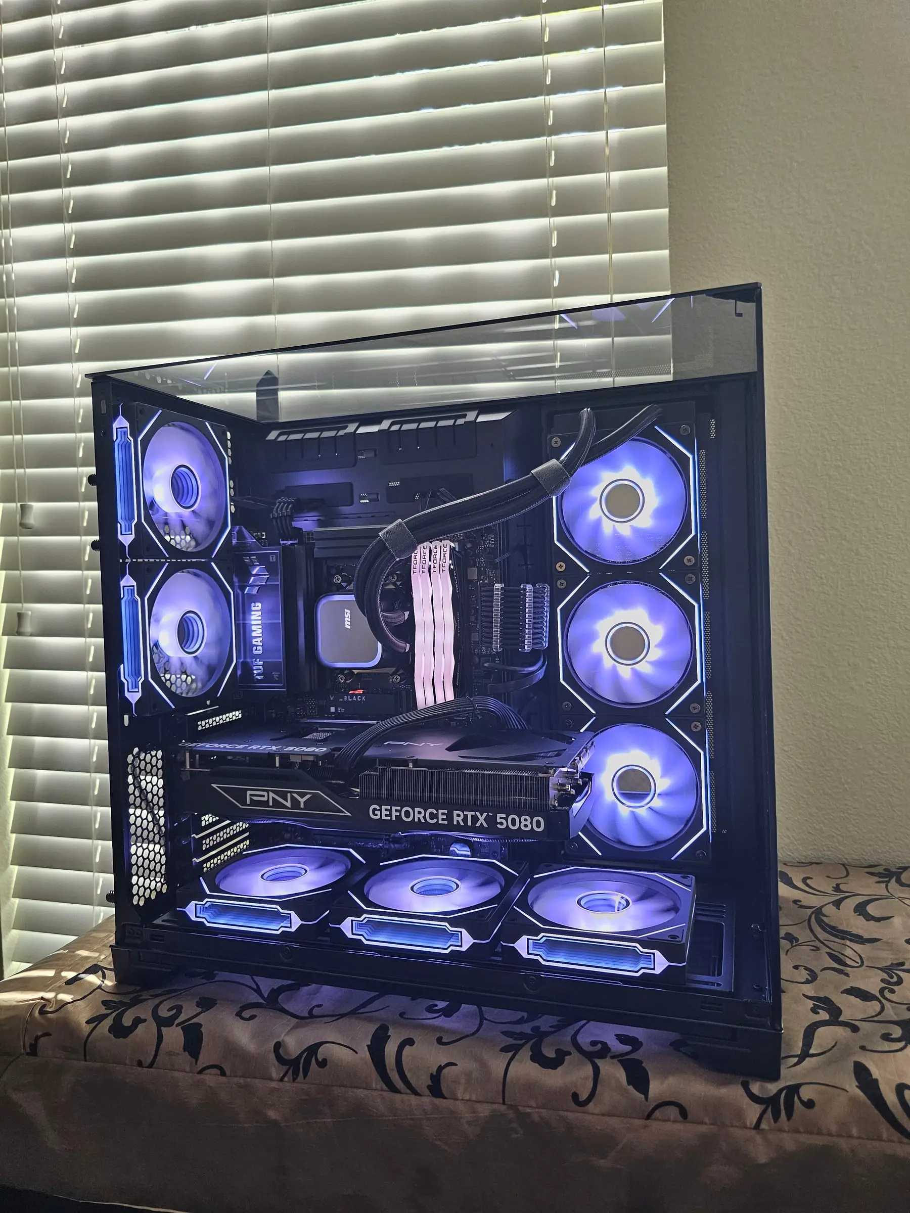 Front-on ice-violet view with the MSI pump, braided AIO lines, and both fan walls lit