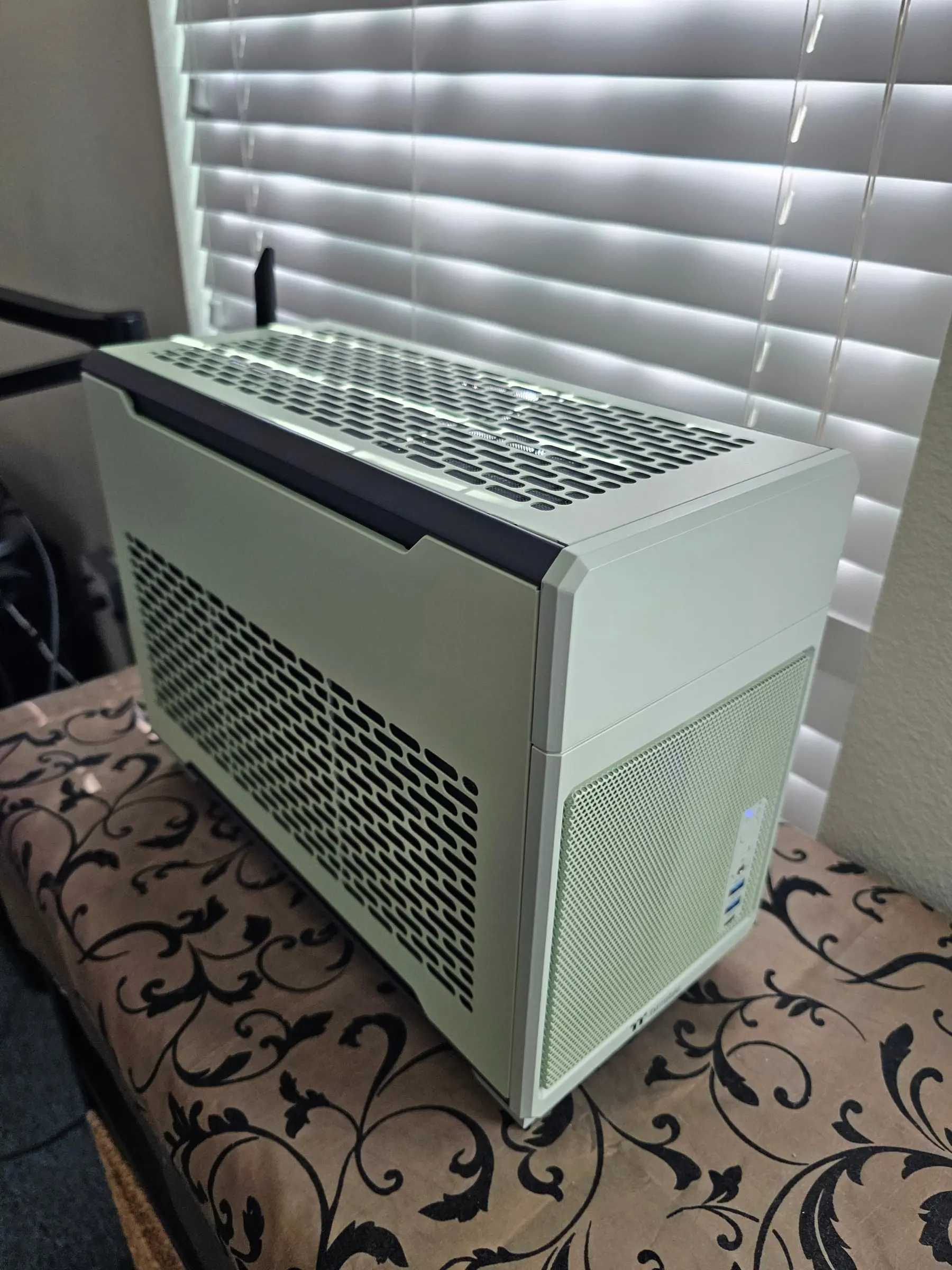 Front-left corner view of the closed matcha green chassis with the rear Wi-Fi antenna visible