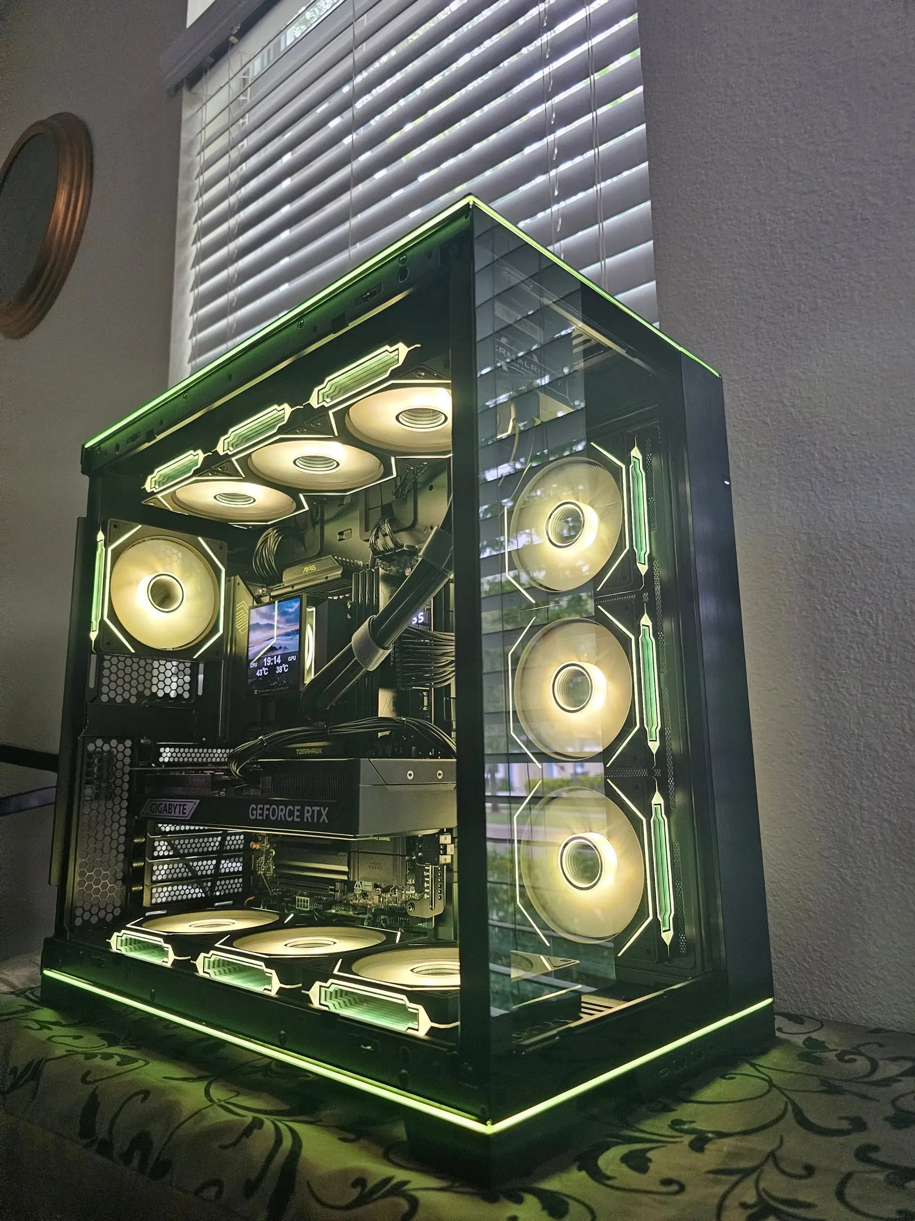 Gold-green theme — Tomahawk board, Windforce RTX and ten warm-lit fans behind the panoramic glass