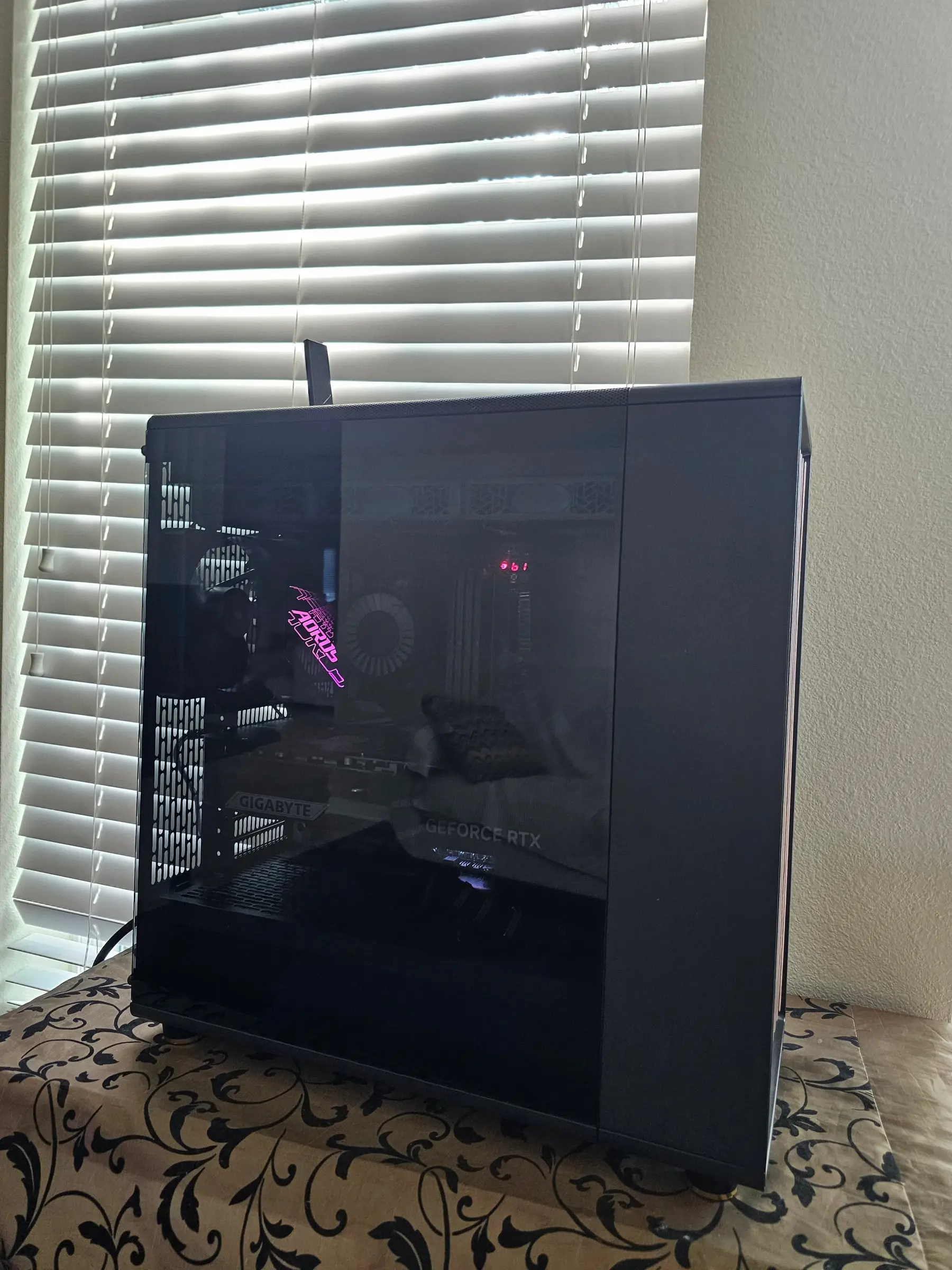 Aorus logo glowing pink through the smoked side panel, power readout lit inside