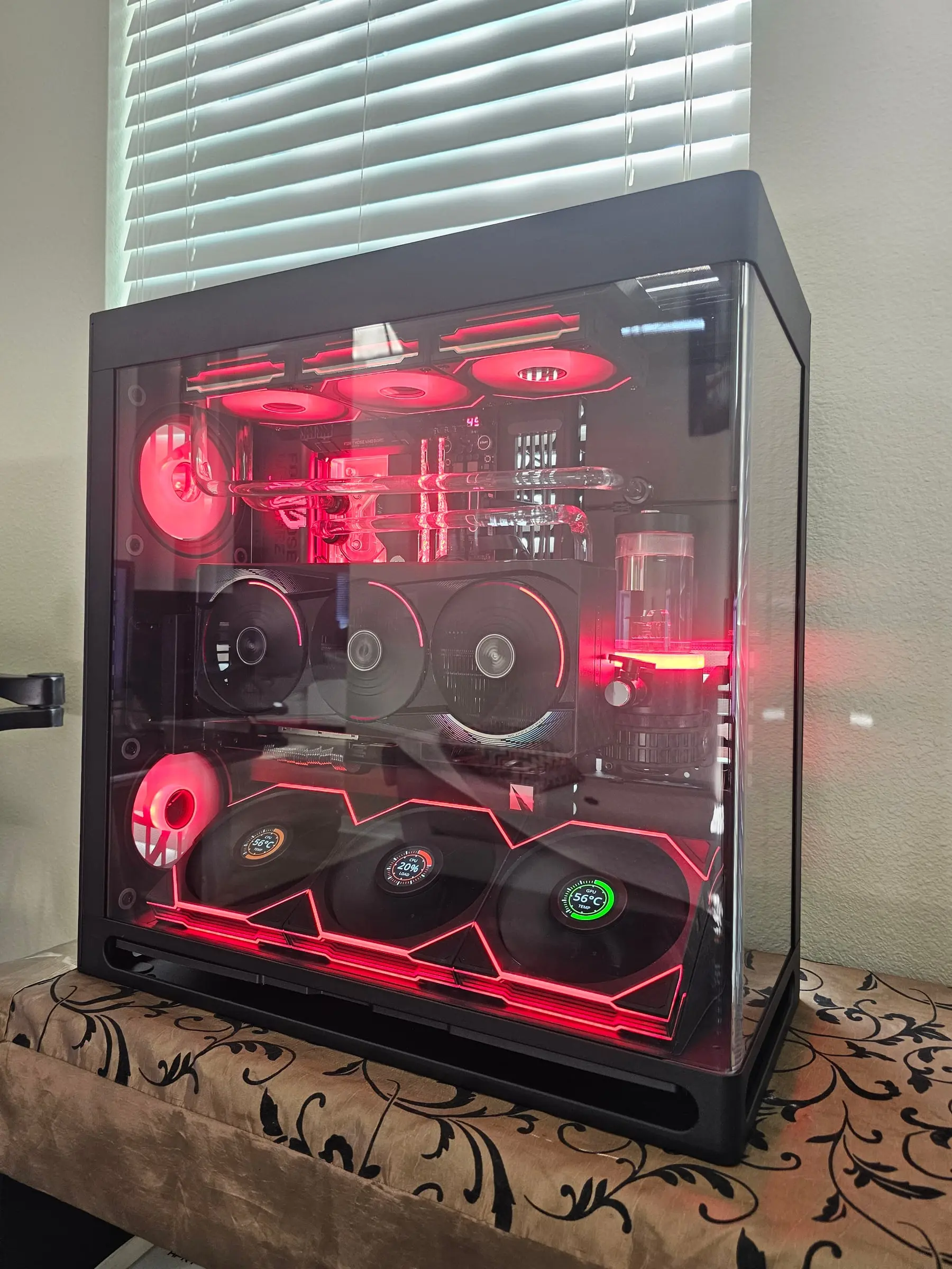 Custom loop lit red — EK block and reservoir glowing, hand-bent acrylic runs, fan LCDs reading live temps
