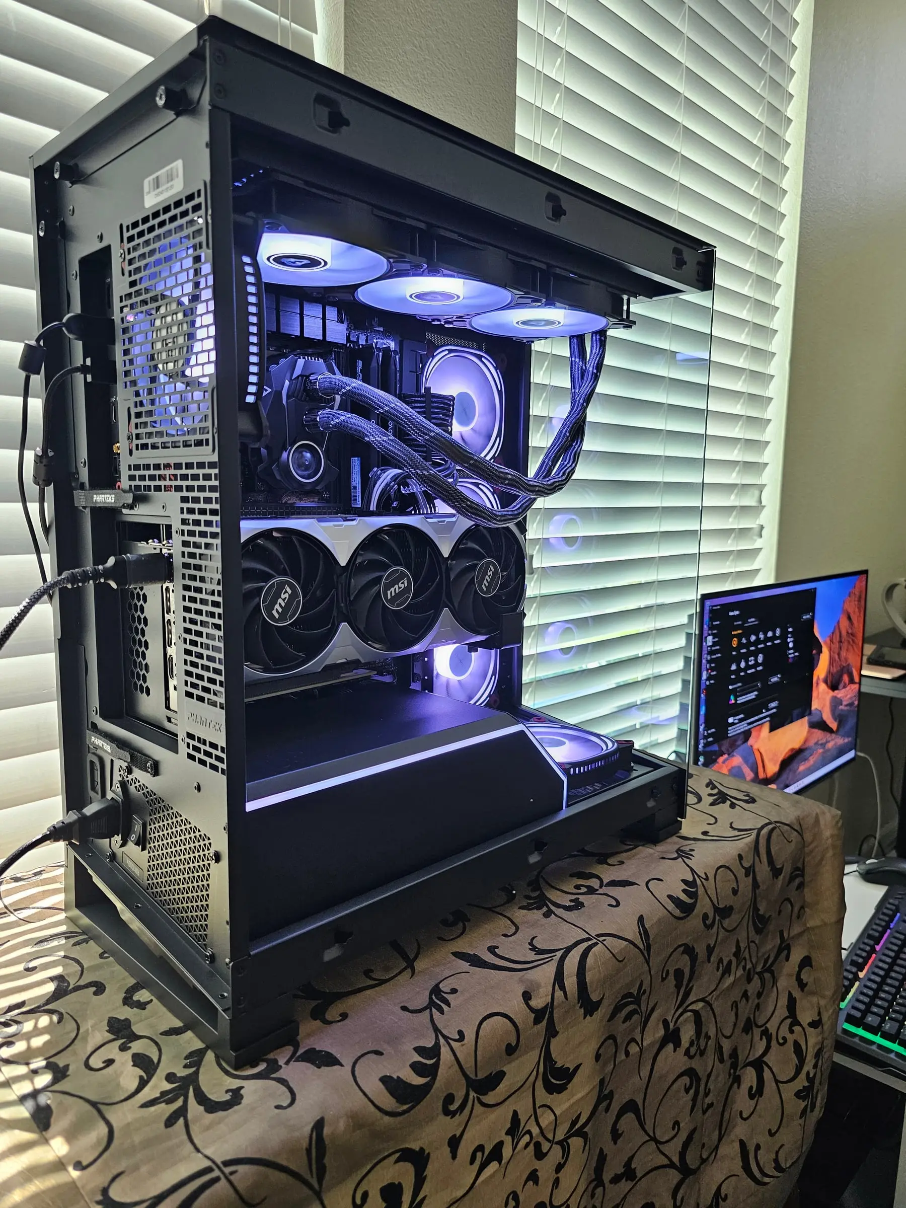 Phanteks NV5 in amber — side fan wall glowing orange through the wrap-around tinted glass