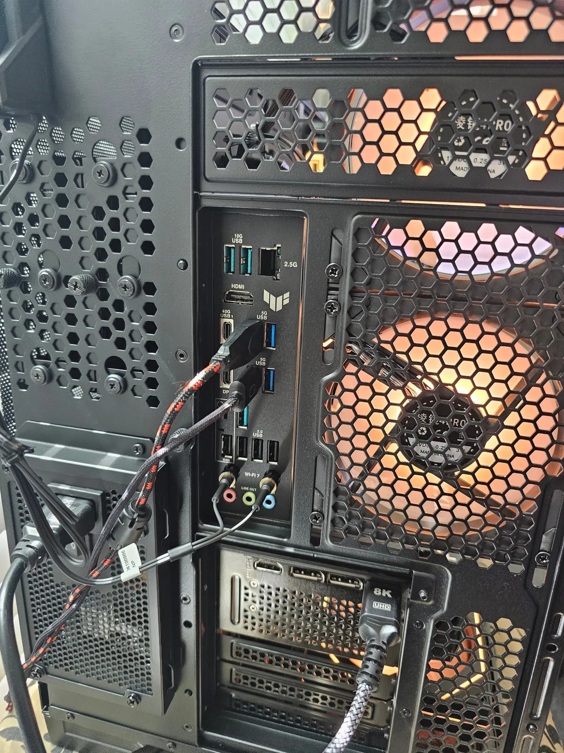Rear I/O of the TUF X870E-Plus — 10G USB, 2.5G LAN, Wi-Fi 7 — with amber fans behind the hex mesh