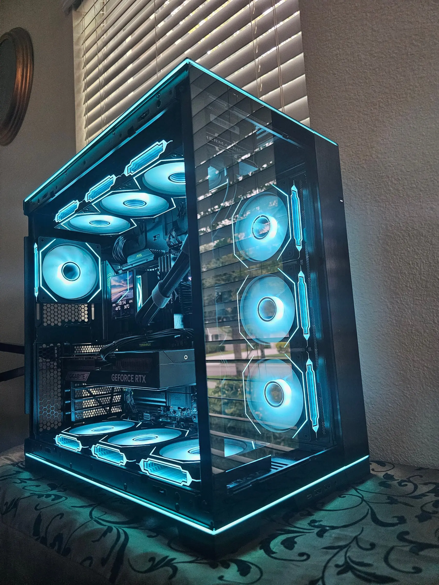 O11 Dynamic EVO RGB in full cyan — edge strips tracing the frame, ten infinity-mirror fans glowing behind glass