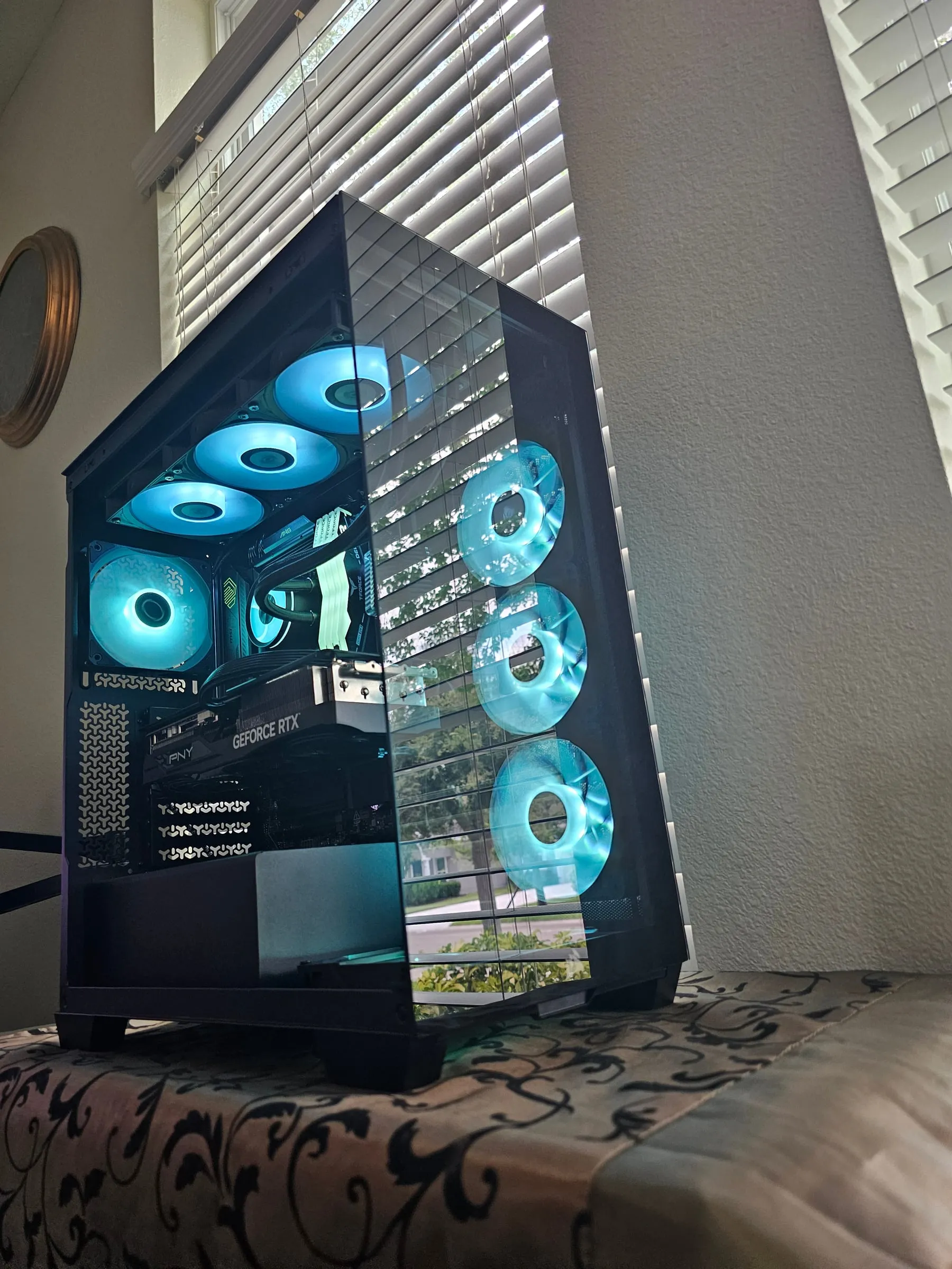 Corsair 3500X glowing cyan from a low angle — wrap-around glass, side fan wall, and the PNY RTX 5070 Ti