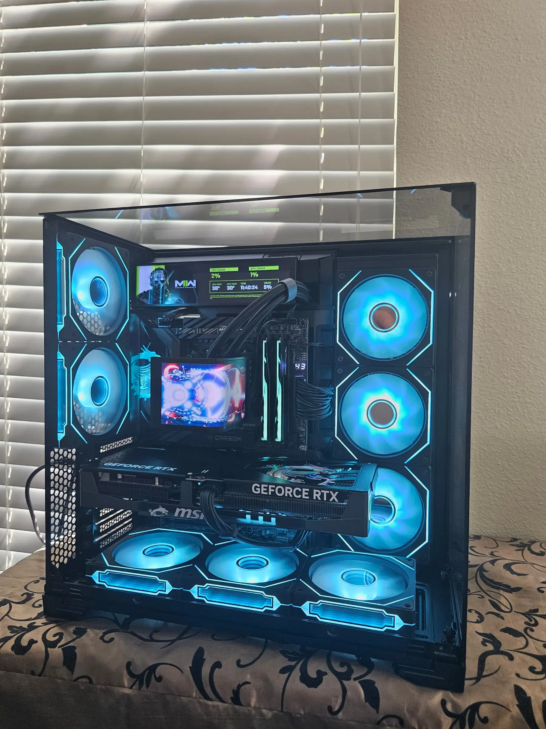 Front-on ice-blue view — Modern Warfare dashboard on the 8.8-inch panel, TRYX AMOLED running art, Gaming Trio 5080 centered
