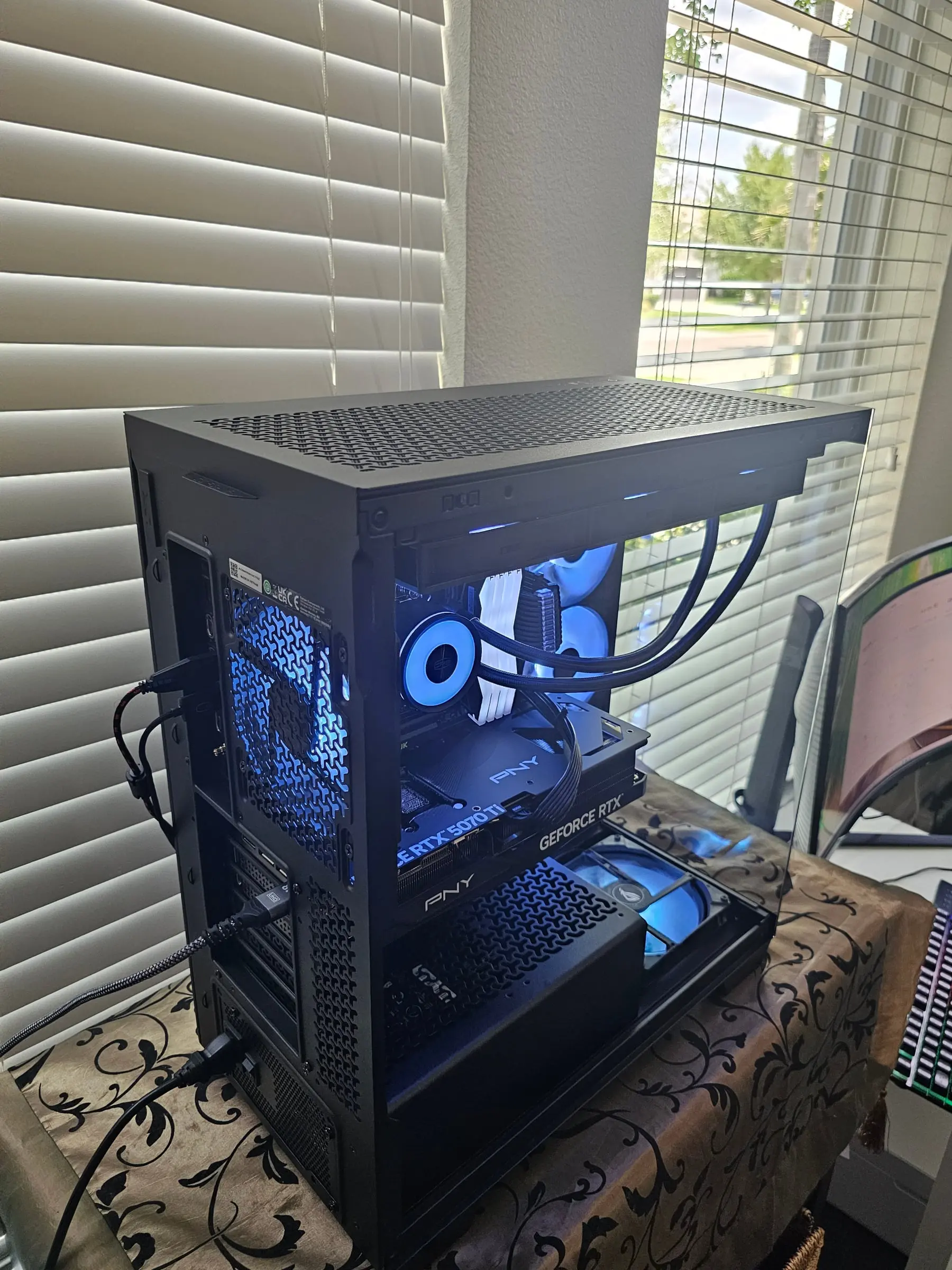 Rear three-quarter with the PNY RTX 5070 Ti badge visible and the loop's tubing routed clean